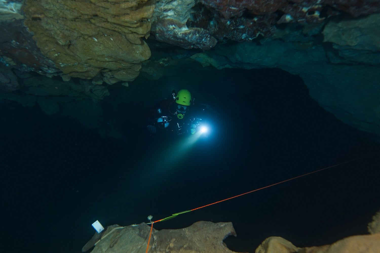 Diver exploring a cave with a torch